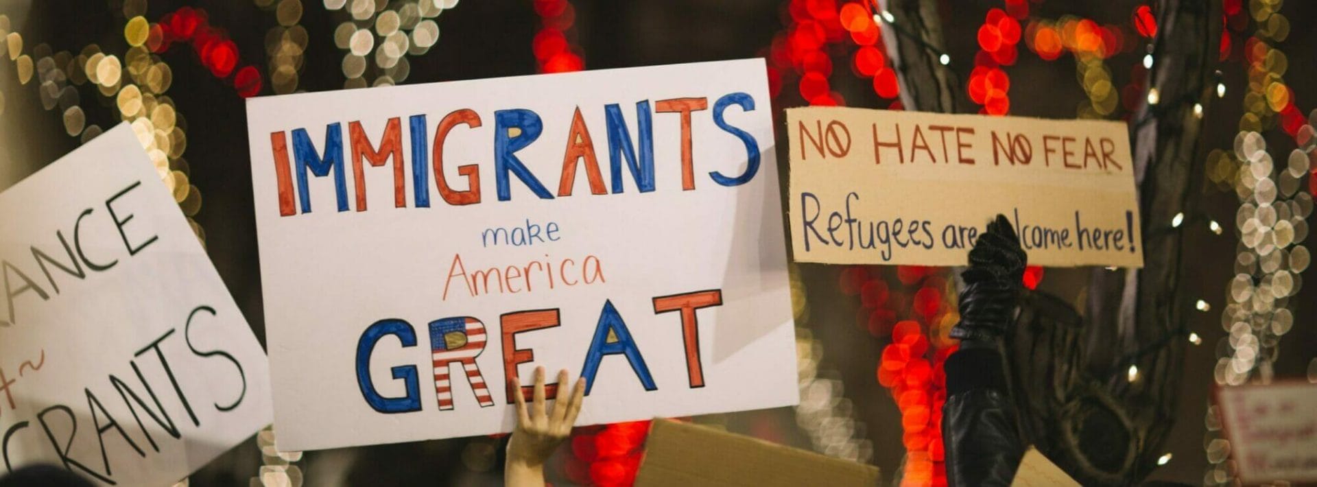 gente sosteniendo carteles que dicen "los inmigrantes hacen a america grande"