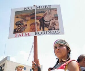 Mujer protestando "no más falsas fronteras" a favor de los migrantes y dreamers y contra las deportaciones