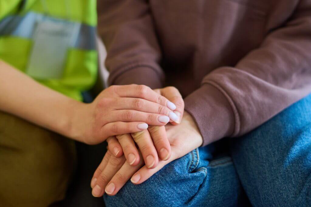 Un voluntario y un refugiado sosteniéndose la mano en señal de apoyo. 